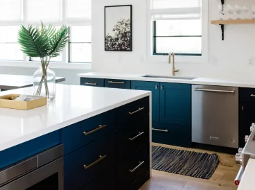 Bright kitchen with white counters and navy cabinets